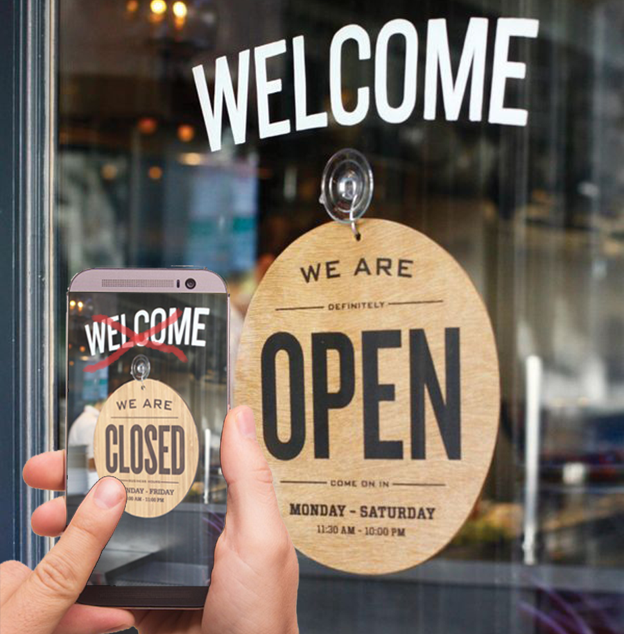 skylten på dörren visar att butiken är öppen men i mobilen som är i handen visar att butiken är stängd